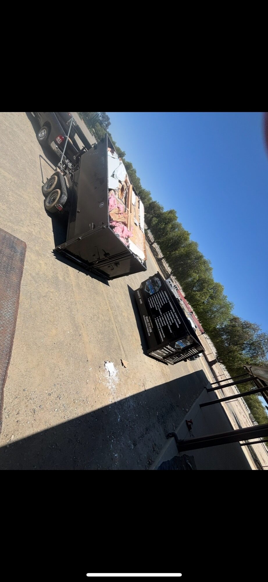Rental dumpster in a residential driveway loaded with renovation debris and drywall next to an OSR-branded dumpster — serving Temecula, Riverside County