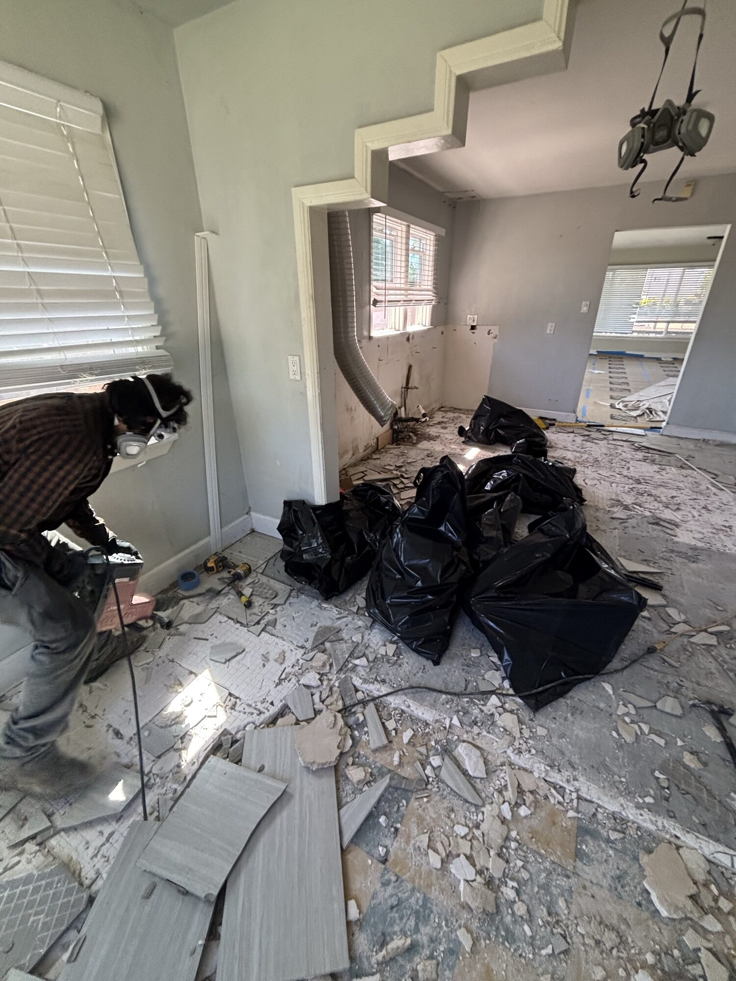 OSR crew member in a respirator breaking up ceramic tile during an interior demolition and haul-out