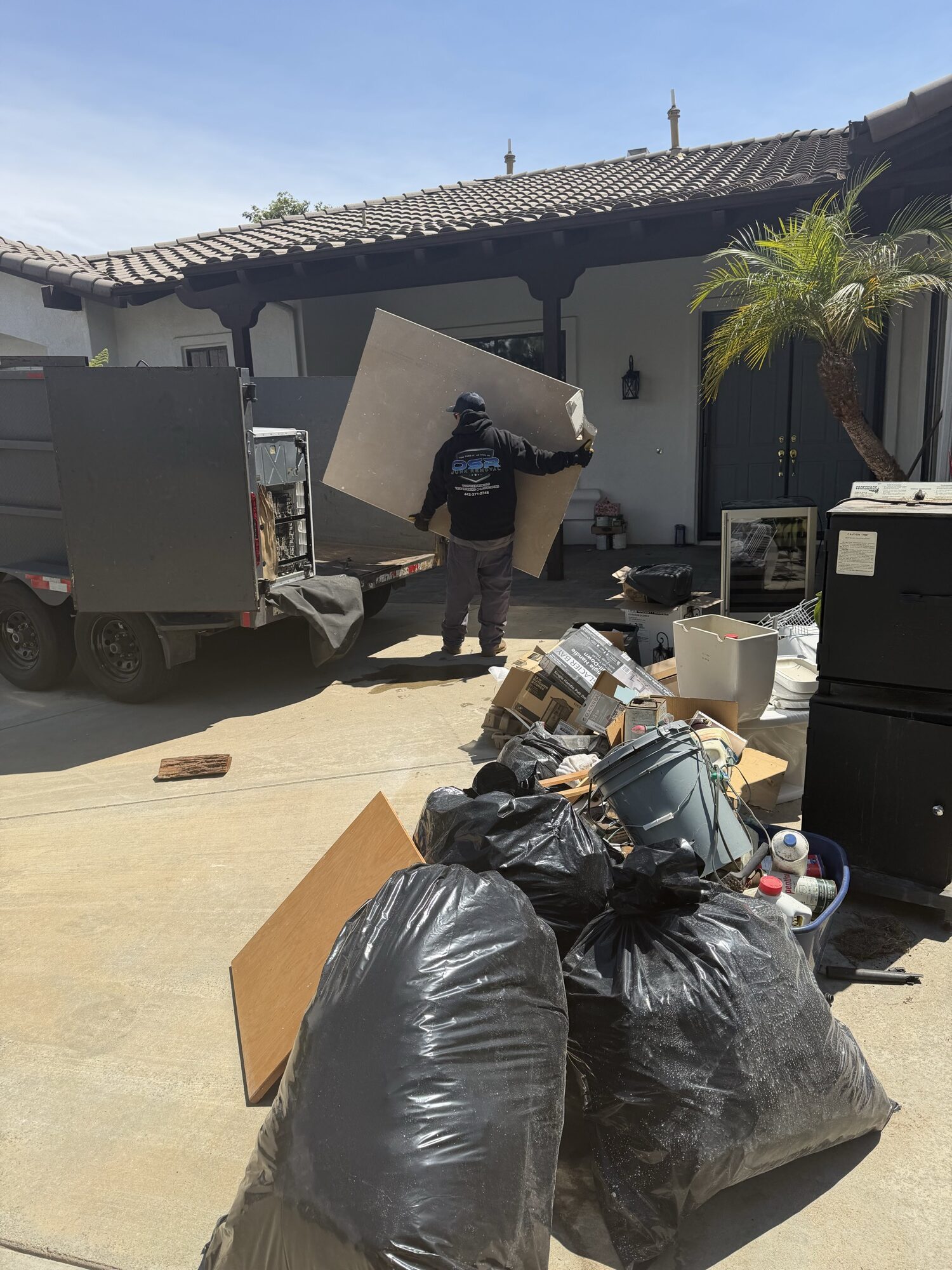 OSR crew member hauling debris from a full-service junk removal and driveway cleanout at a Fallbrook home in North County San Diego