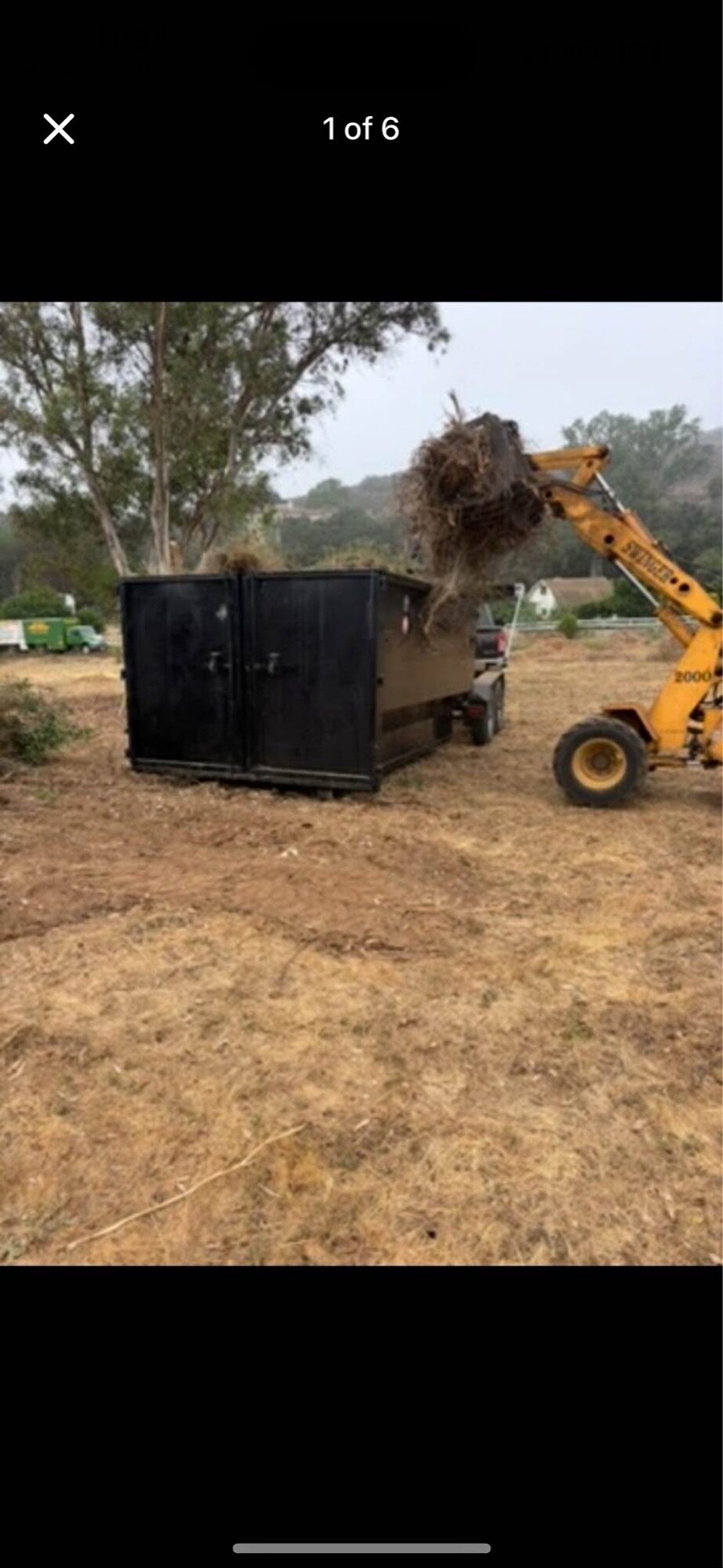 Telehandler loading brush and cleared vegetation into a black OSR dumpster during a land clearing job in Fallbrook — serving Rainbow, San Diego County