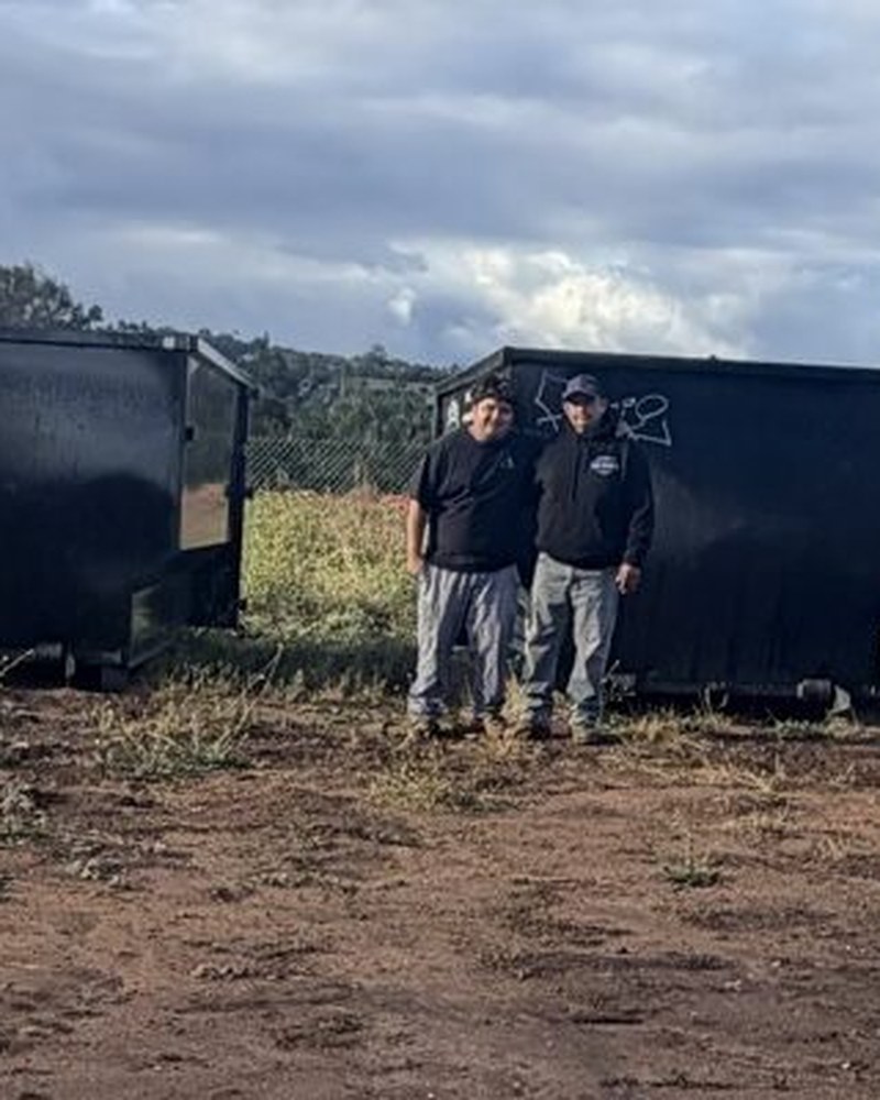 Oscar and Oscar Sr., the family owners of OSR, standing together in front of one of their dumpsters in Fallbrook, CA