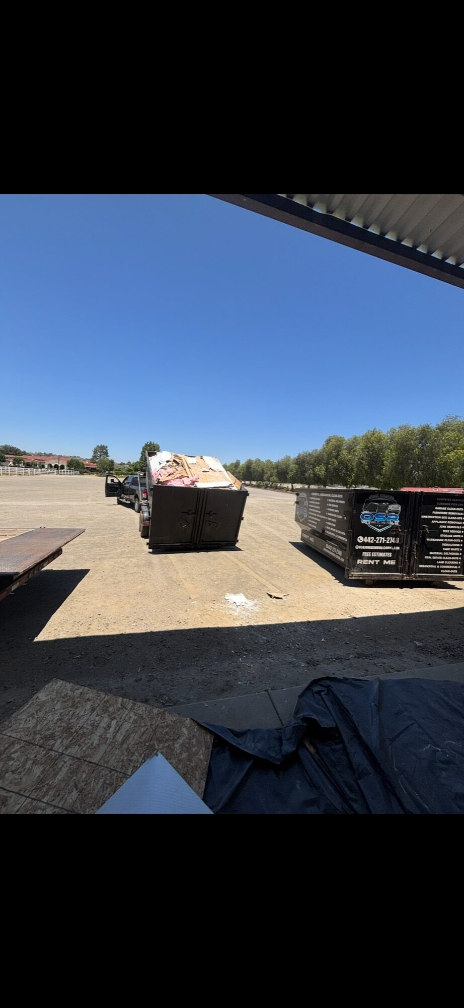 OSR-branded roll-off dumpster staged next to a loaded haul truck at a North County San Diego job site